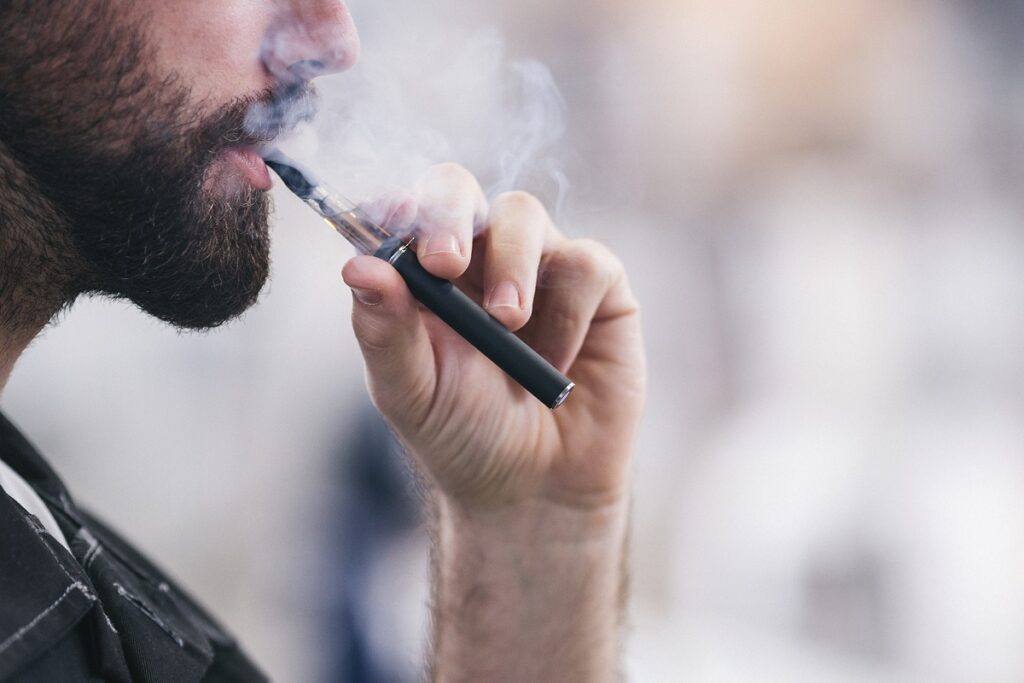 Person vaping with a black e-cigarette