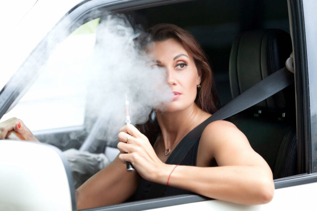 Woman vaping in a car, smoke visible.