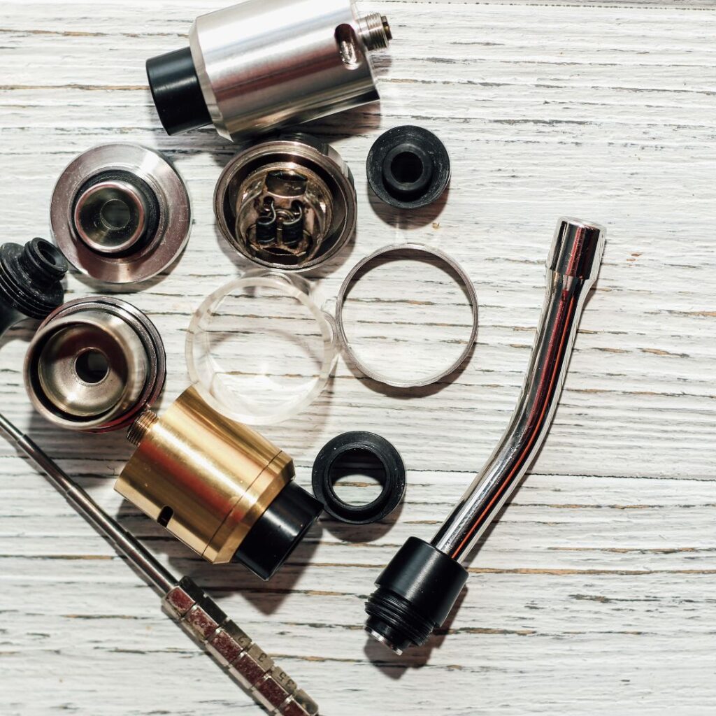 Disassembled vape components on a wooden surface.