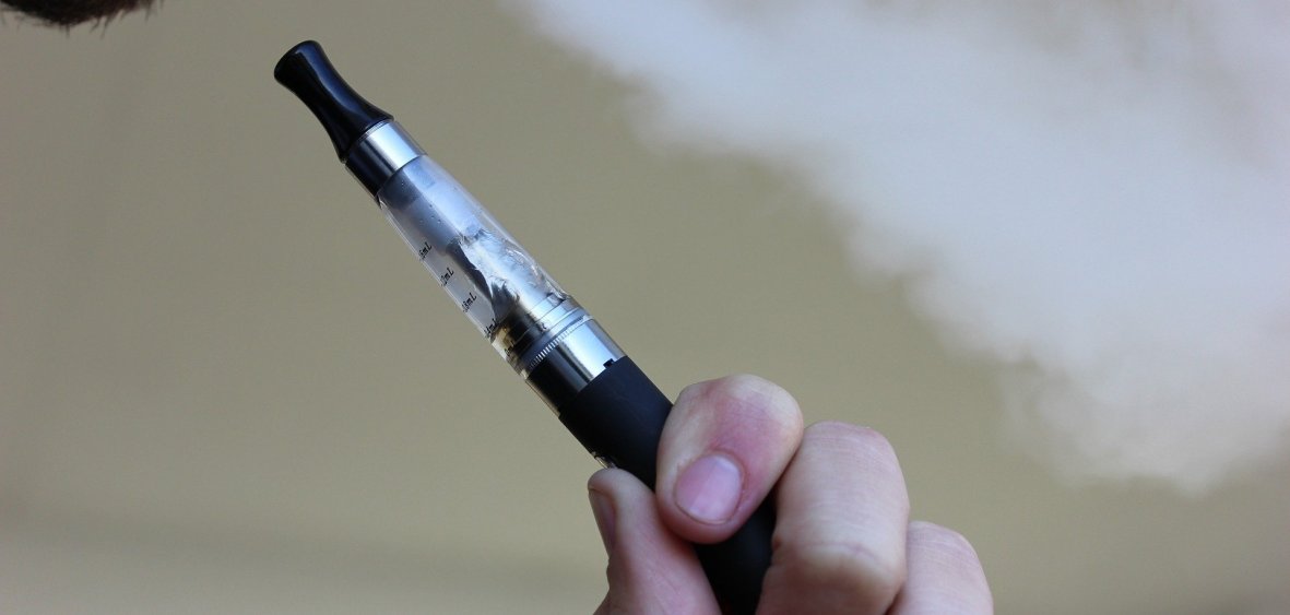 E-papieros lub bateria litowo-jonowa, z której wydobywają się iskry lub dym, symbolizujące ryzyko pożaru.