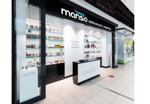 Widok na schludne i dobrze oświetlone wnętrze profesjonalnego sklepu z e-papierosami, z widocznym asortymentem i ladą obsługi.