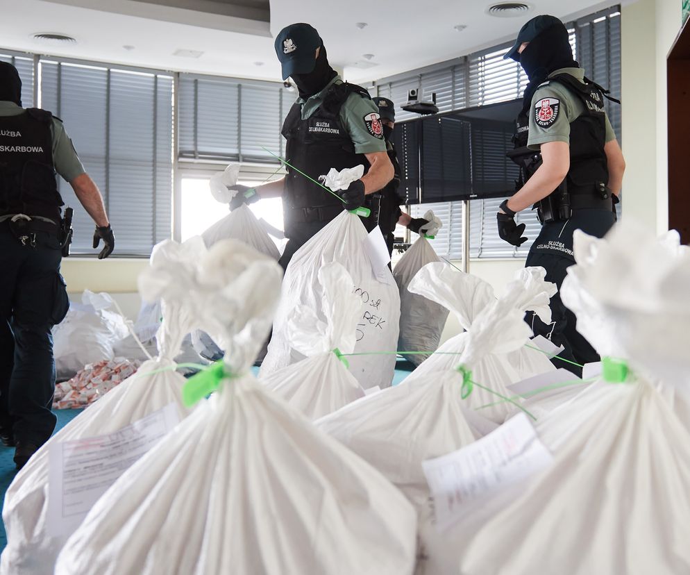 Ciemna, niejasna uliczka lub zaułek symbolizujący szarą strefę, z sylwetkami osób dokonujących podejrzanych transakcji, sugerującymi nielegalny handel e-papierosami.