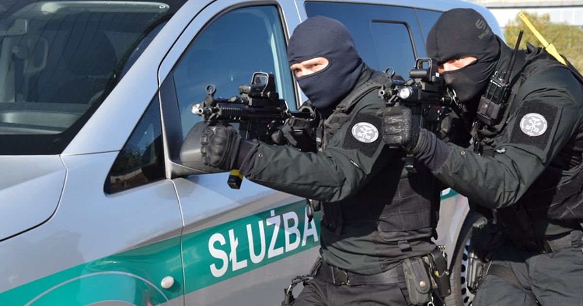 Smutny mężczyzna (Pan Marek) stojący obok pustych półek w sklepie lub stosu skonfiskowanego towaru przez służby, symbolizujący upadek biznesu.