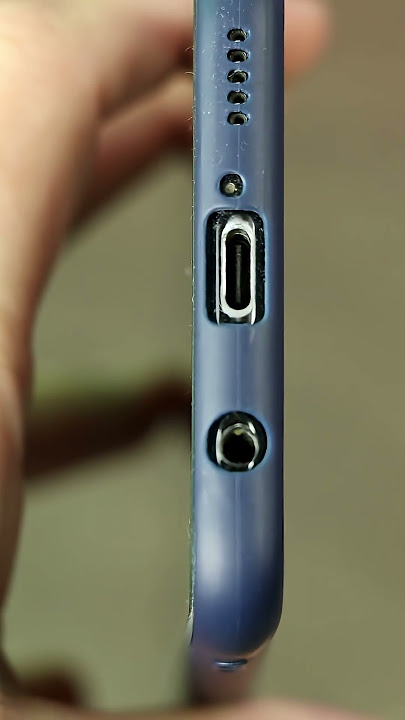 Graficzne, mocne zbliżenie na port USB-C w e-papierosie, pokazujące nagromadzony kurz i kłaczki.