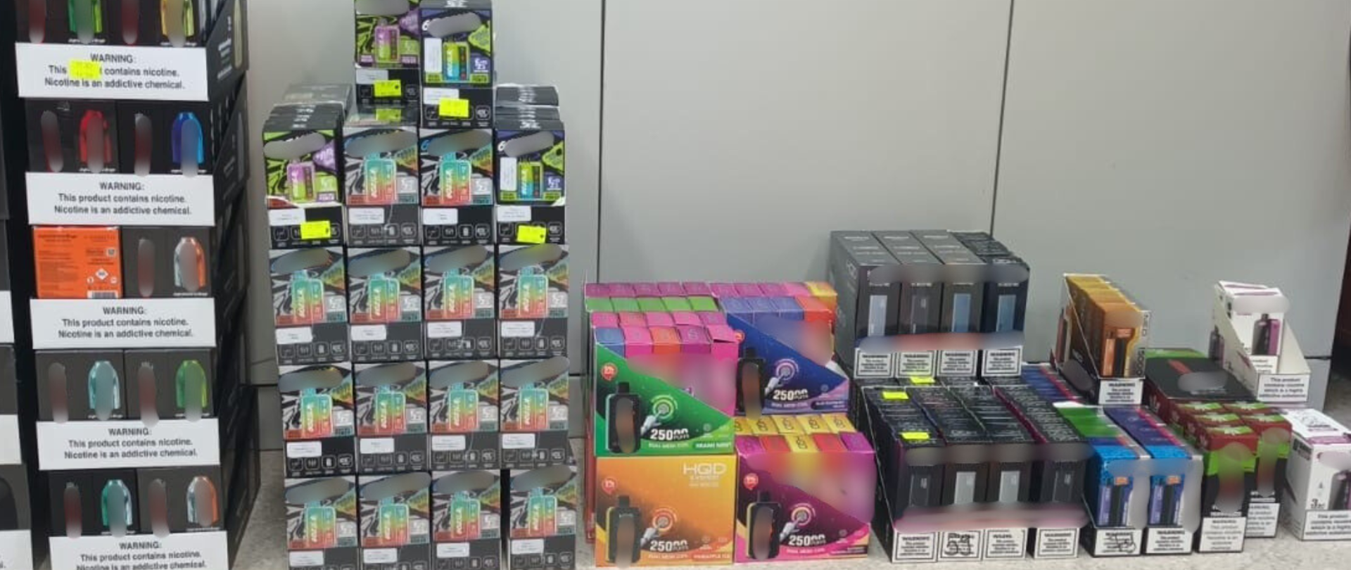 Mroczny, niehigieniczny garaż z prowizorycznym sprzętem do produkcji e-papierosów lub liquidów, z symbolami ostrzegawczymi o niebezpieczeństwie.