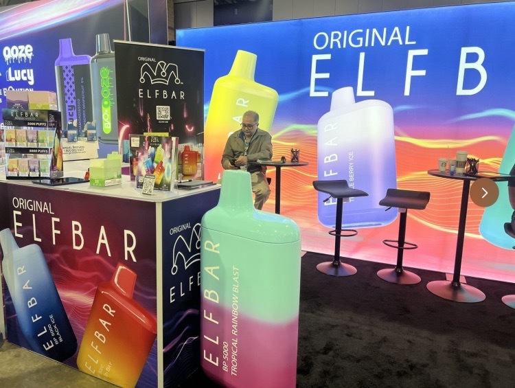 Korona spoczywająca na e-papierosie Elfbar, otoczona znakami ostrzegawczymi i symbolami fałszerstw, podkreślająca jego status najczęściej podrabianego produktu.