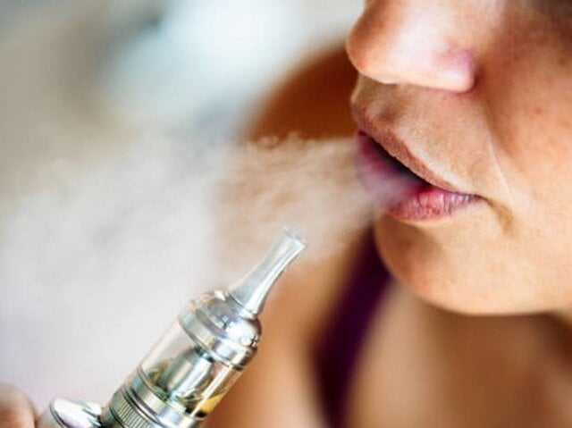 Ręce w sterylnych rękawiczkach chirurgicznych, trzymające e-papieros jednorazowy i skalpel, symbolizujące analizę i