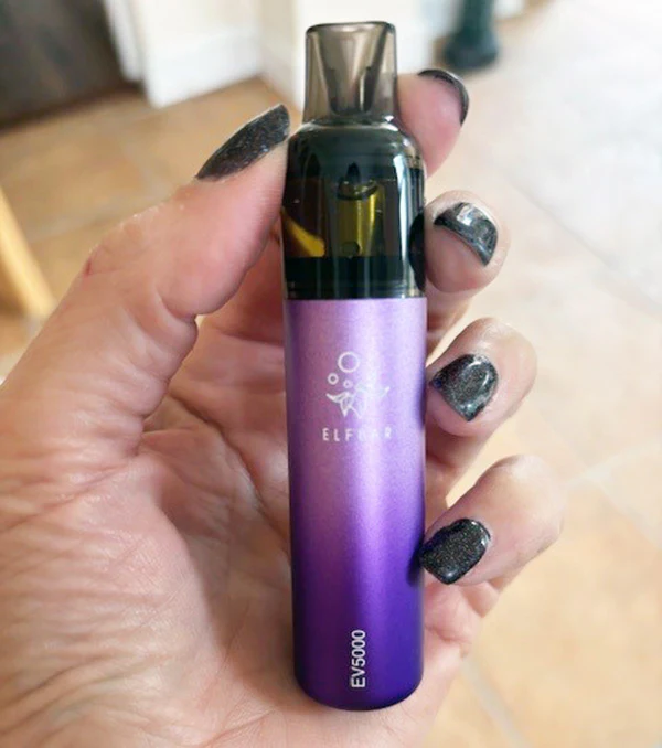 Dłoń delikatnie trzymająca e-papieros Elfbar BC5000, podkreślająca jego komfortowy, 'otoczakowy' kształt i miękkie w dotyku materiały.