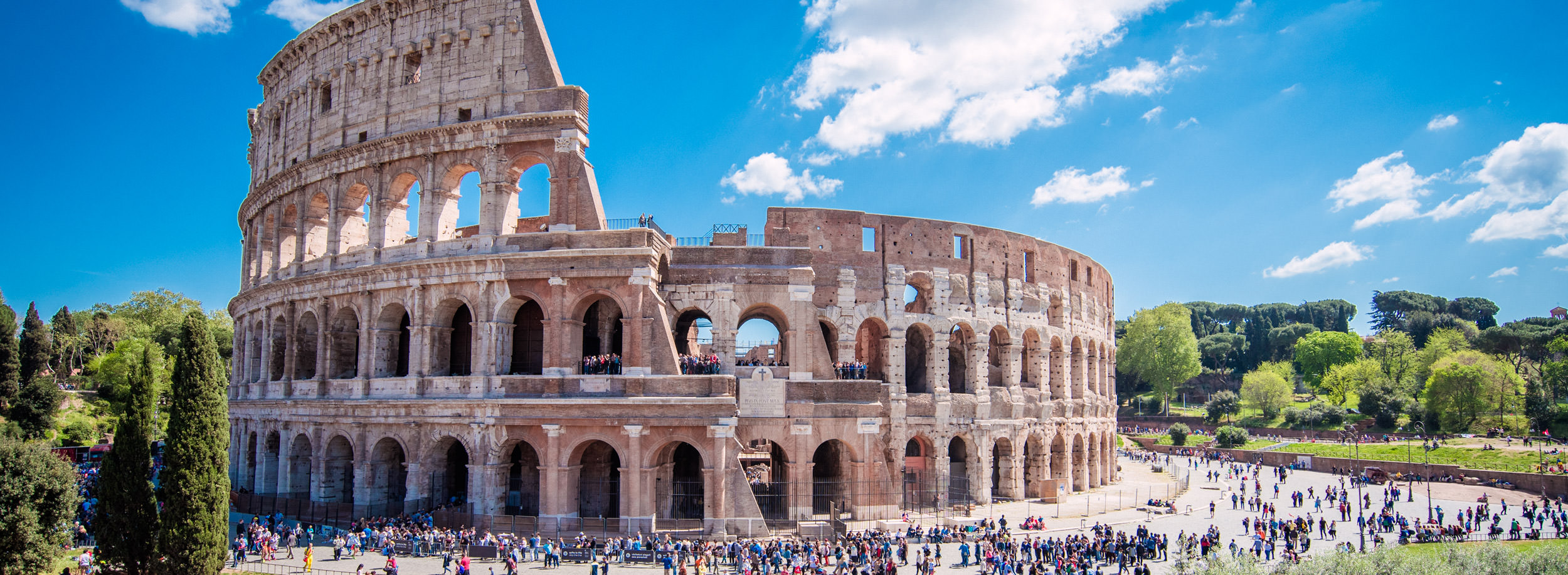 Malownicze zdjęcie Koloseum w Rzymie, z dodatkowymi elementami pizzy i kieliszka wina na pierwszym planie, symbolizujące nagrodę za oszczędności.
