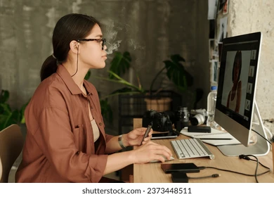 Zdjęcie osoby siedzącej przy biurku z komputerem, grającej lub oglądającej serial, z dużym e-papierosem jednorazowym obok, symbolizujące wygodę użytkowania w domu.