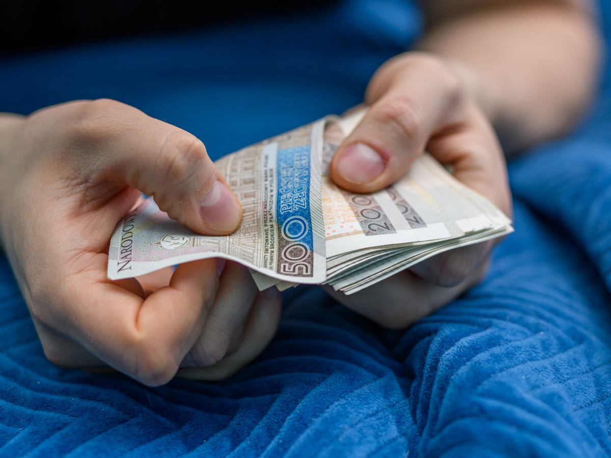 Osoba trzymająca głowę w szoku, a obok niej spadające lub ulatujące pieniądze, symbolizujące ogromne koszty palenia.